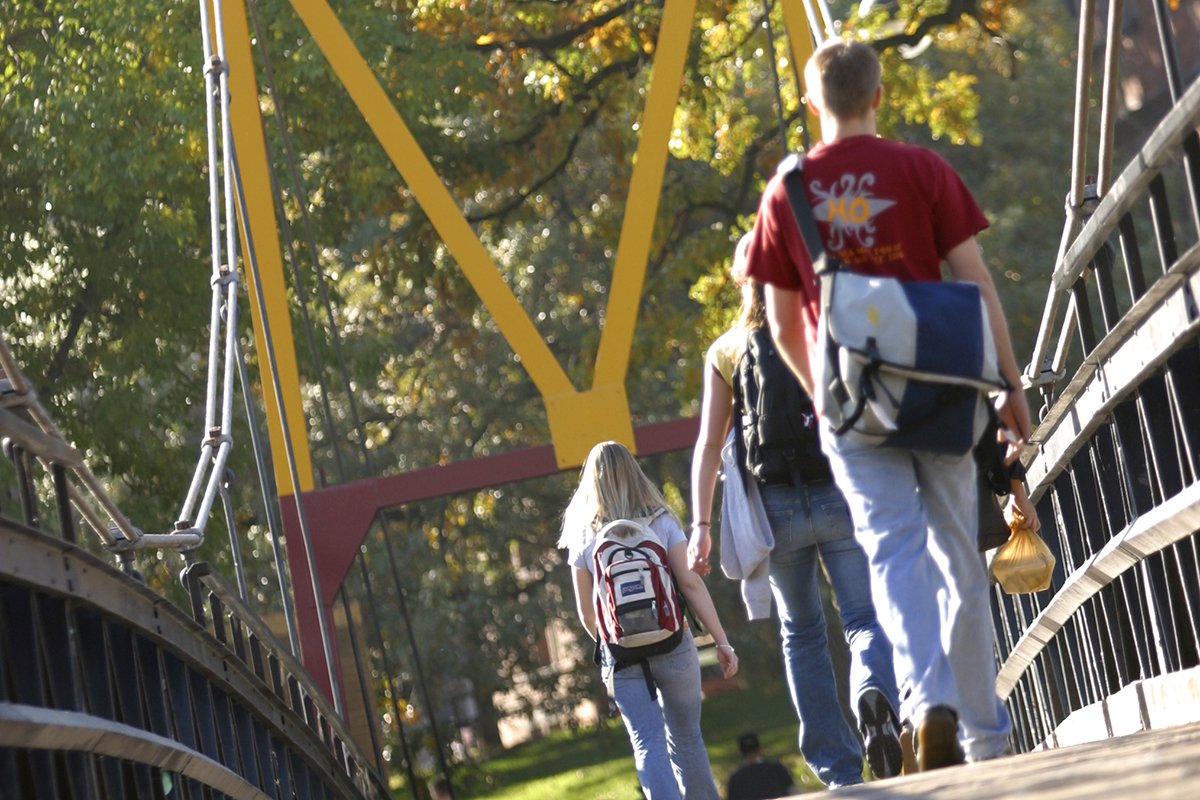 students walking across big M bridge on campus